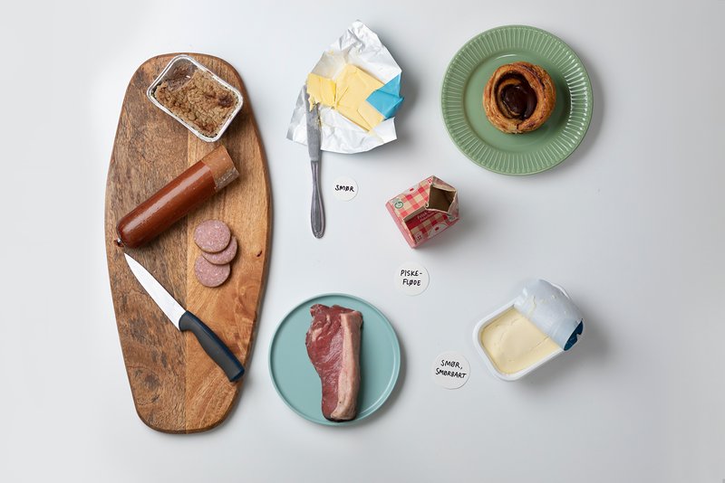 Eksempler på fedtkilder med mættet fedt: Smør, piskefløde, smør i smørbar version, weinerbrød, leverpostej, en rød bøf og spegepølse.
